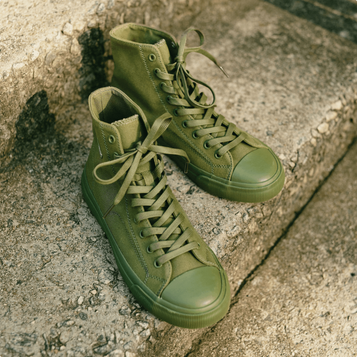 Olive green high-top sneakers on a stone step.