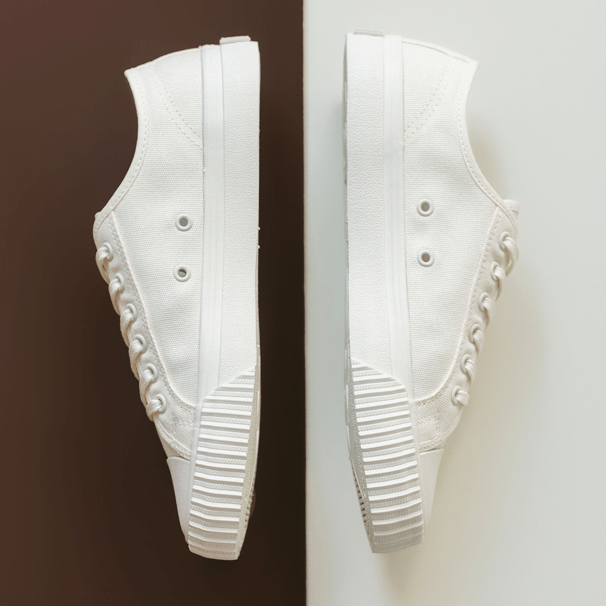 White low-top sneakers on a white and brown background.