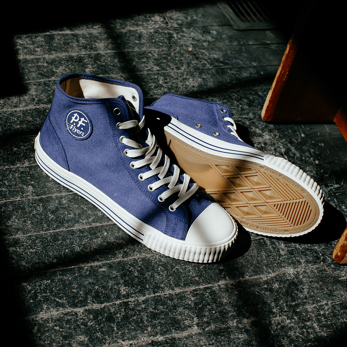 Blue high-top sneakers with white soles illuminated by natural light.