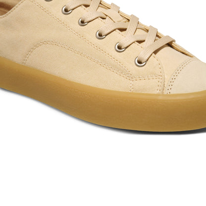 Close-up of a beige sneaker with a tan sole on a white background.