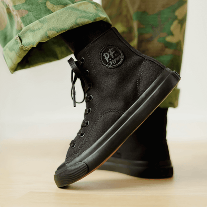 Black high-top sneakers on a wooden floor. 