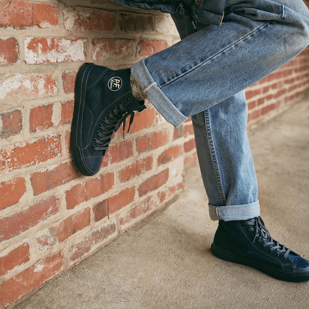 Navy high-top sneakers pressed on a brick wall.