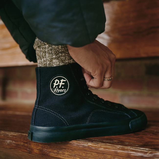 Navy high-top sneakers pressed on a wooden step.