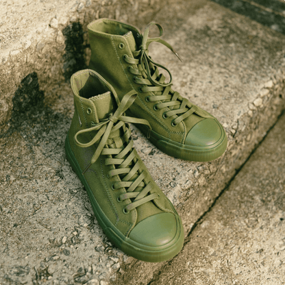Olive green high-top sneakers on a stone step.