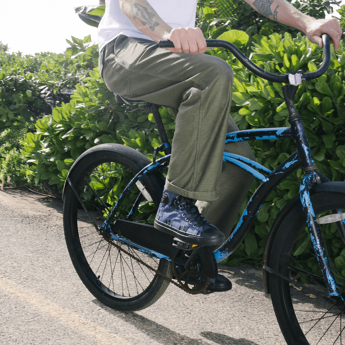 Person riding a blue bicycle on a paved path with greenery in the background