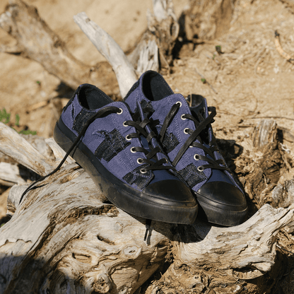 Pair of blue sneakers with black soles on a wooden log