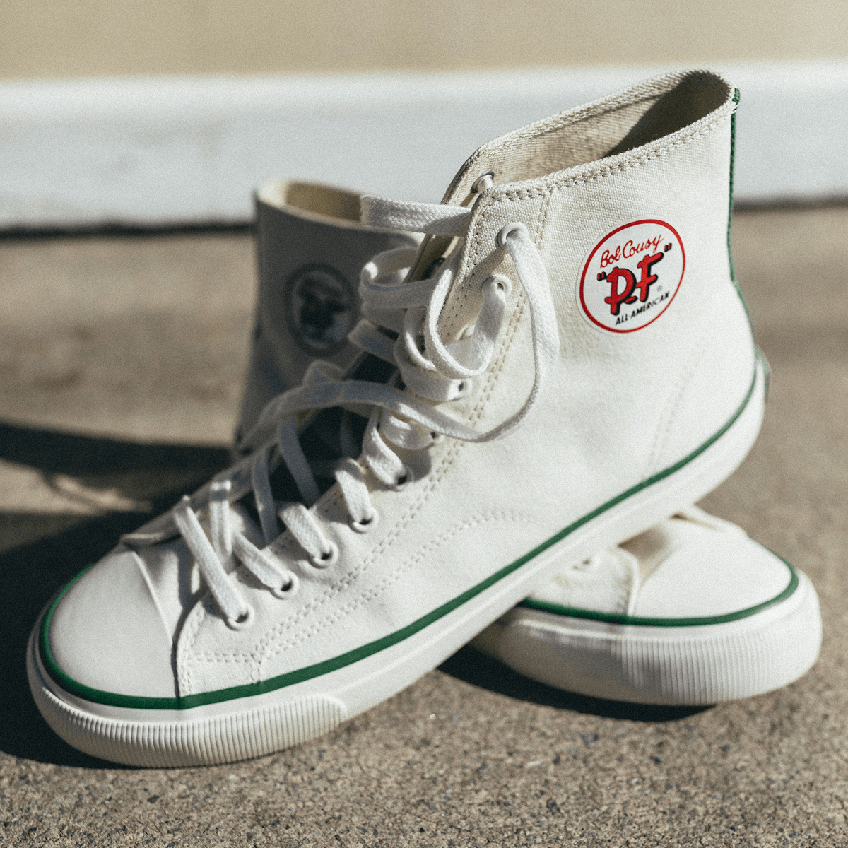 White high-top sneakers on a concrete surface.