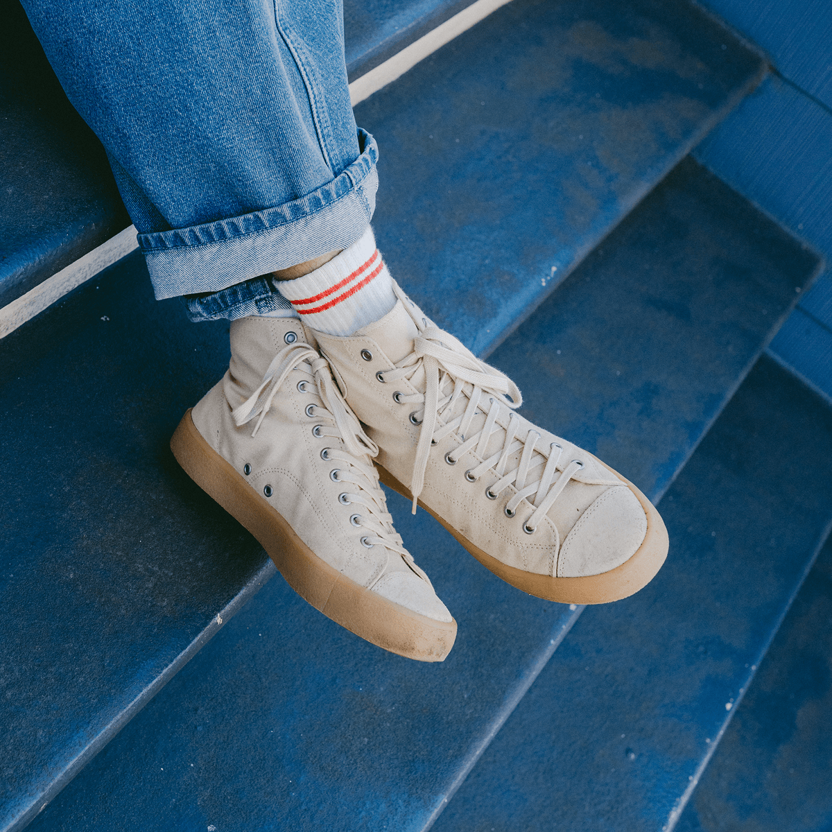 Beige high-top sneakers with tan soles on blue steps.