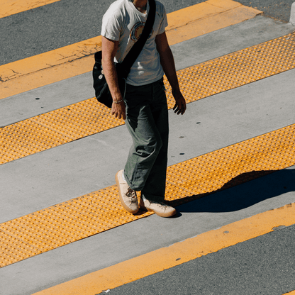 Person walking on a crosswalk wearing beige low-top sneakers.