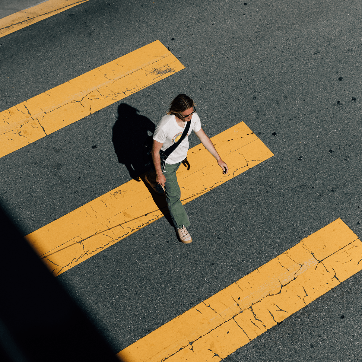 Person walking on a crosswalk wearing beige low-top sneakers.