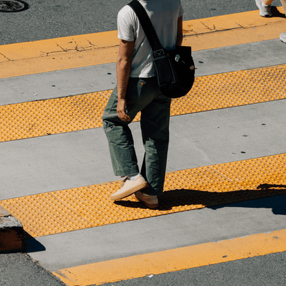 Person walking on a crosswalk wearing beige low-top sneakers.