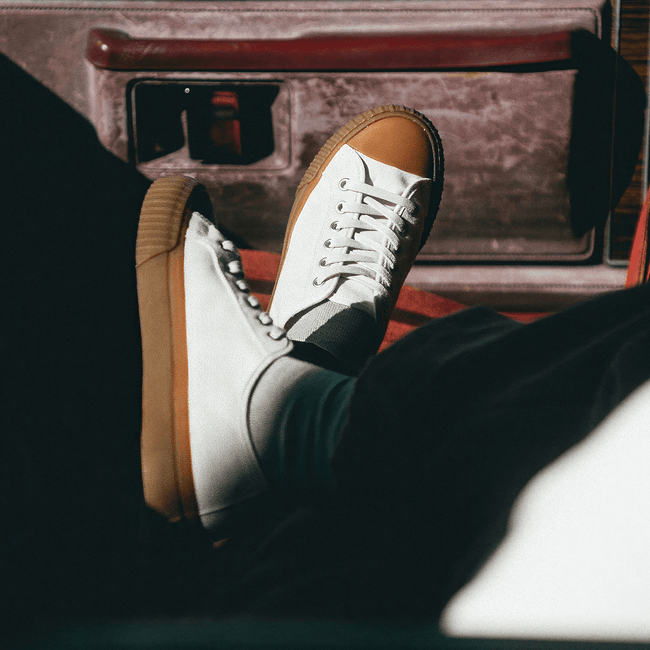 White sneakers with brown soles on a person's feet while sitting inside a vehicle.