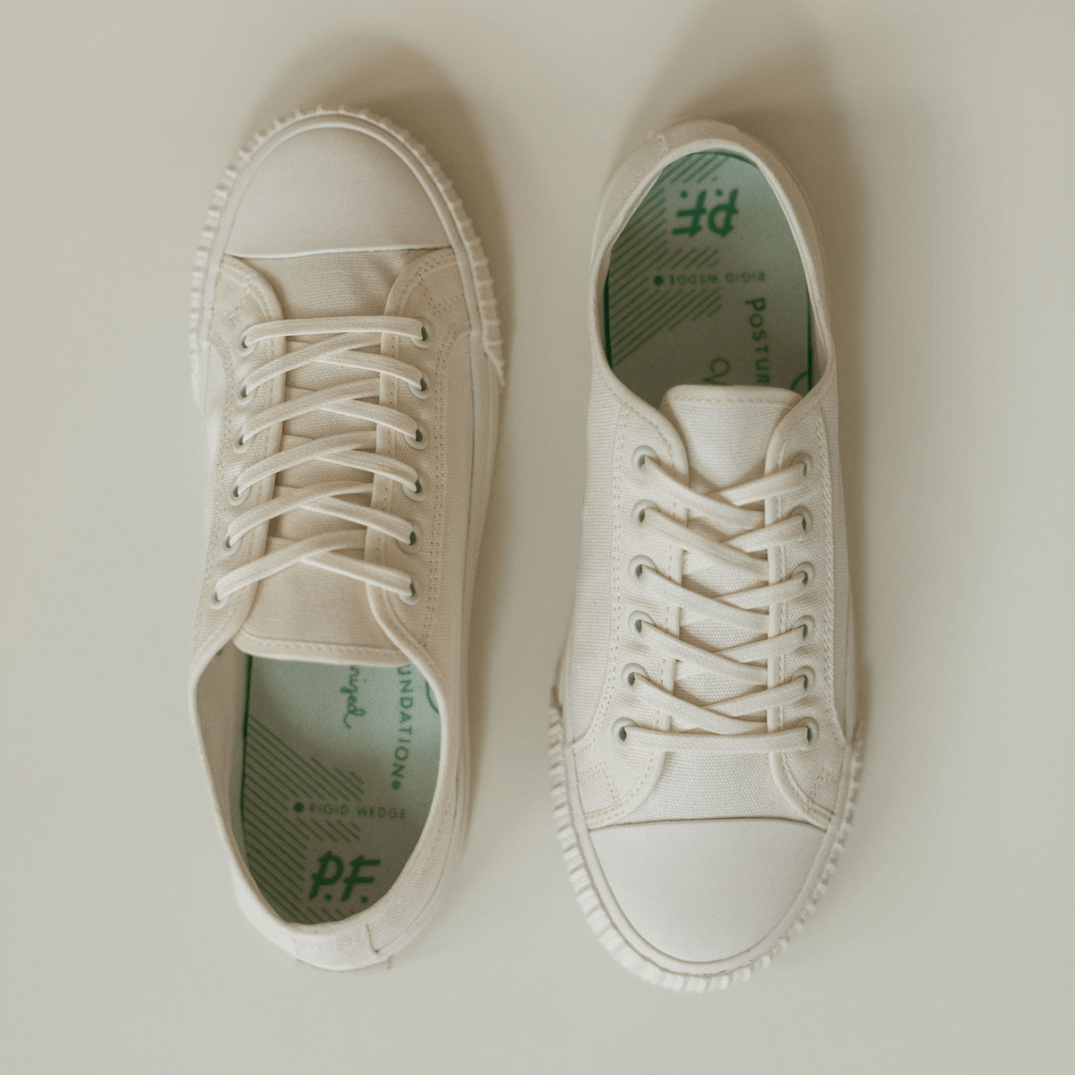 Pair of white low-top sneakers on a light background.