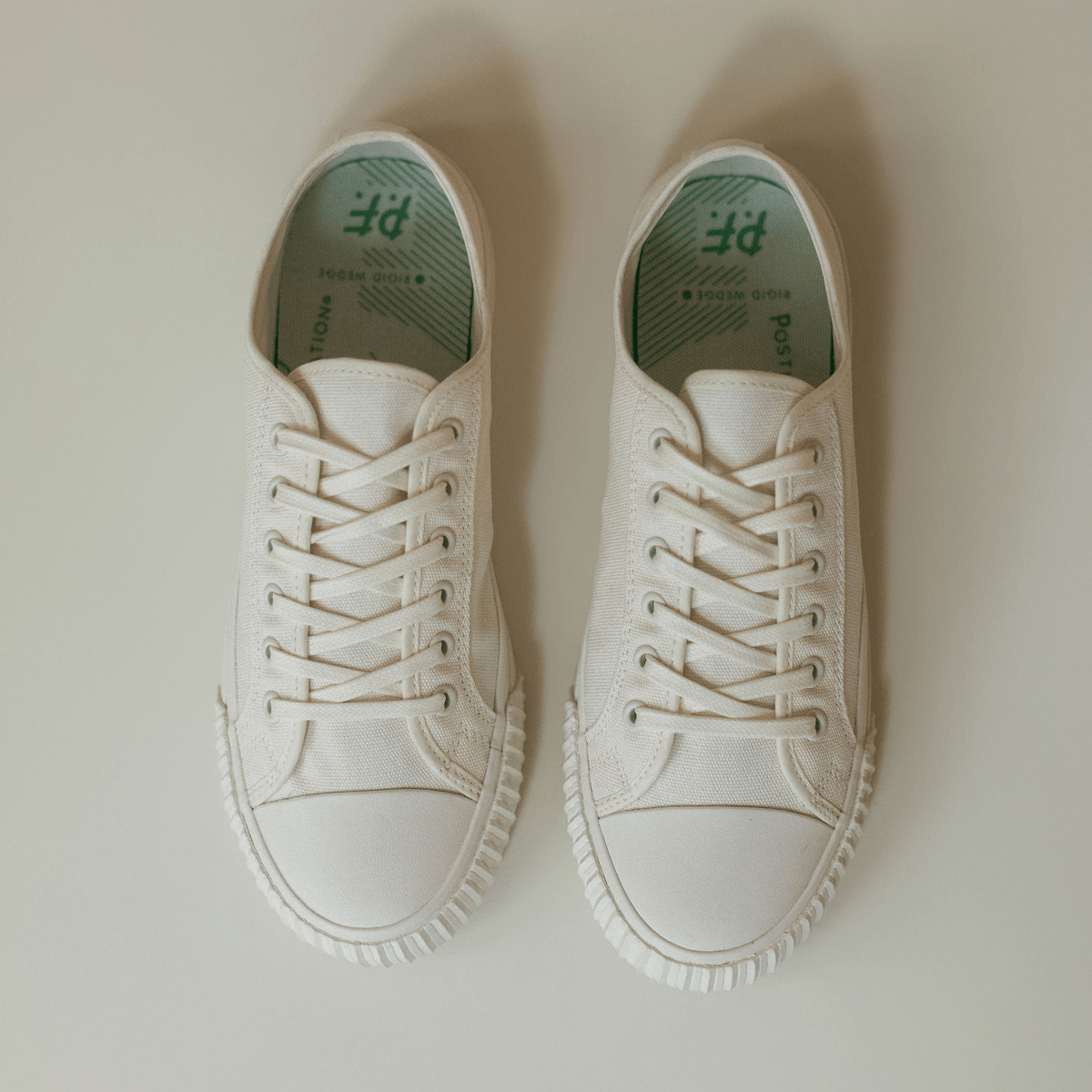 Pair of white low-top sneakers on a light background.