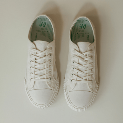 Pair of white low-top sneakers on a light background.