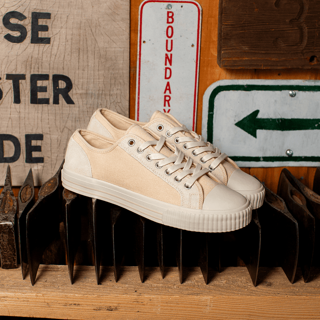 Beige low-top sneakers on a metal surface with a rustic background.