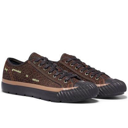 Brown low-top sneakers on a white background, with “Stay grounded in nature” embroidered on the upper.
