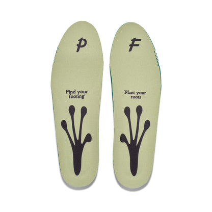 Pair of green shoe insoles on a white background, featuring a frog foot silhouette and the phrases “Find your footing” and “Plant your roots” printed on them.