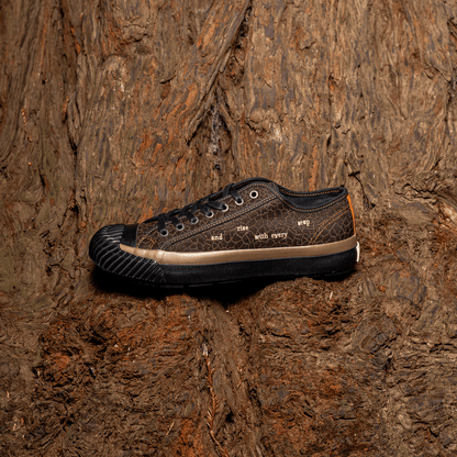 Brown low-top sneakers with black soles on a natural wooden surface.