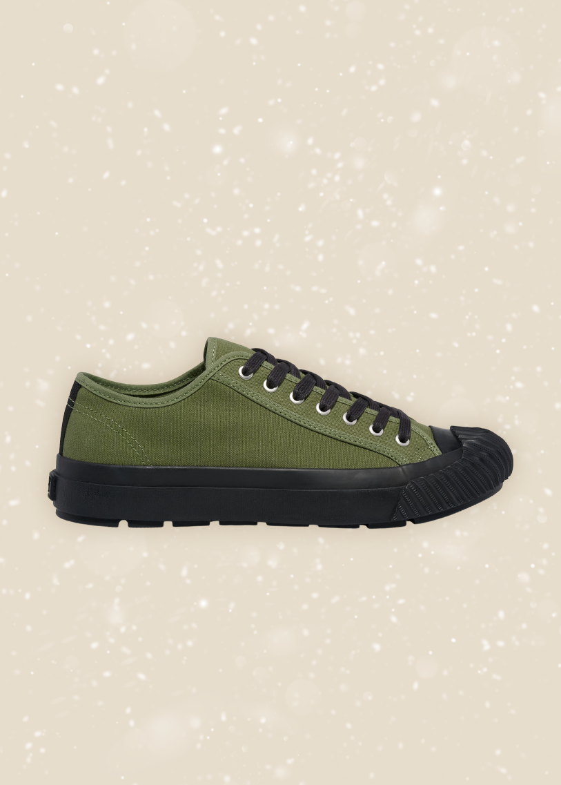 Green sneaker with black sole on a beige background