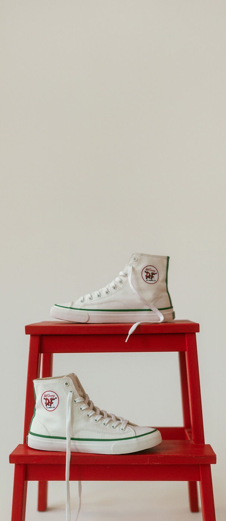 P.F. Flyers All-American High-Top Cousy on a red chair
