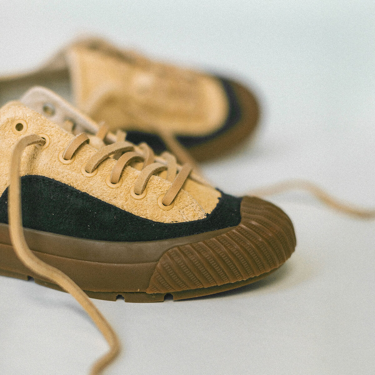 Pair of suede tan and black sneakers on a light background