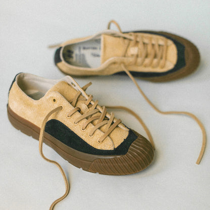 Pair of tan sneakers with black accents on a light gray background