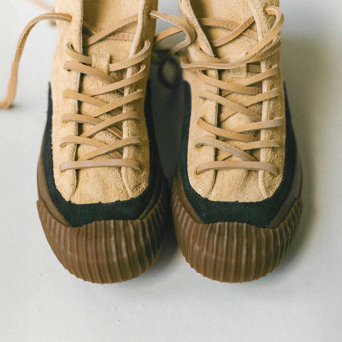 Pair of tan suede sneakers with black accents on a light background