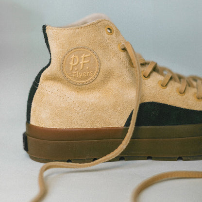 Tan high-top sneaker with black accents and 'PF Flyers' logo on a light gray background