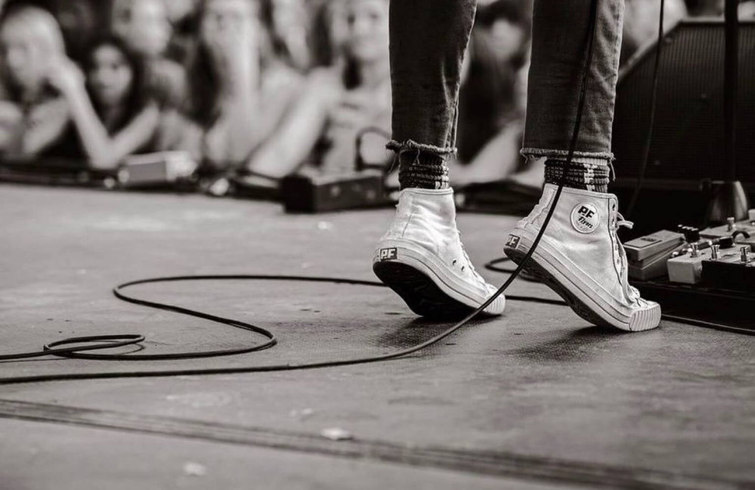 Guitarist wearing PF Flyers on stage at a concert